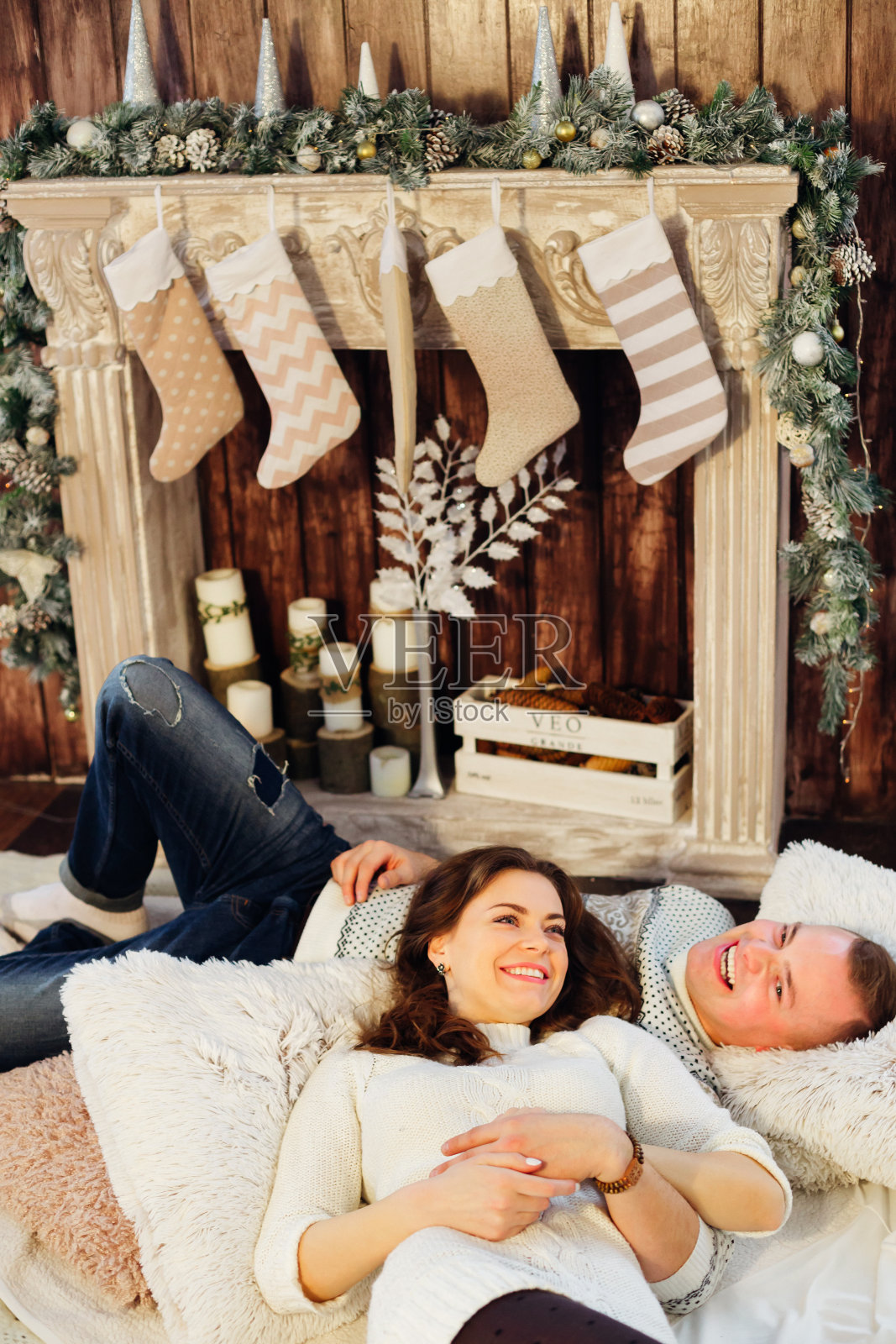 一对美丽的年轻夫妇躺在客厅的地板上，旁边是一个照片摄影图片