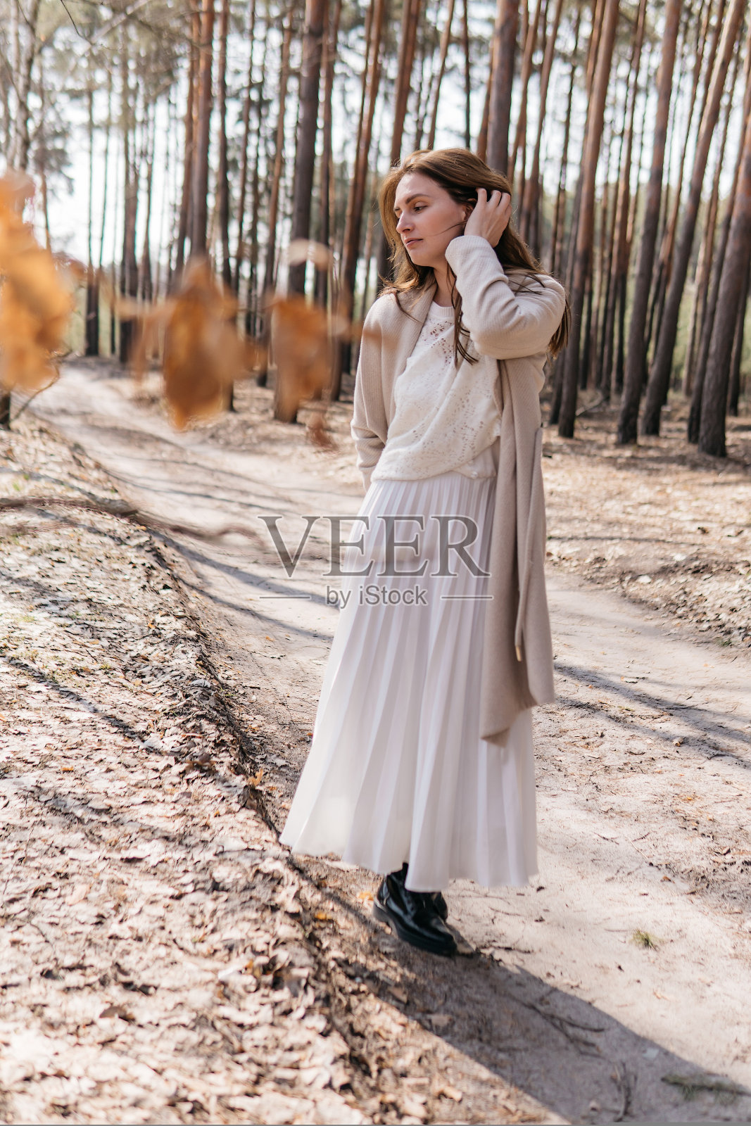 在春天白桦林中穿着白色连衣裙和米色外套的漂亮女人照片摄影图片