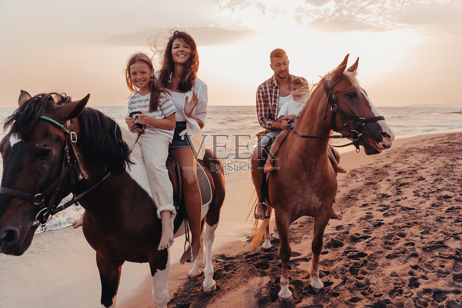 一家人和孩子们一起在沙滩上骑马。有选择性的重点照片摄影图片