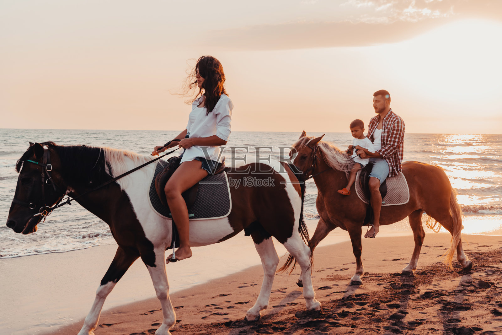 一家人和孩子们一起在沙滩上骑马。有选择性的重点照片摄影图片