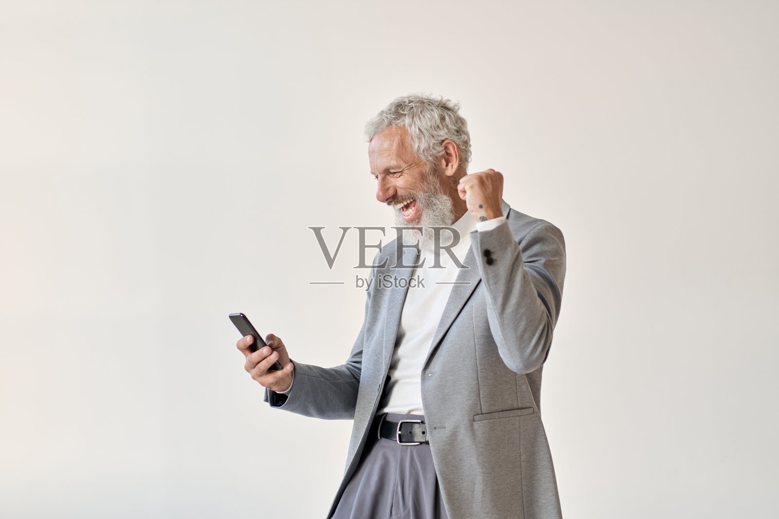 兴奋快乐的老商人投资者举起拳头使用智能手机。照片摄影图片