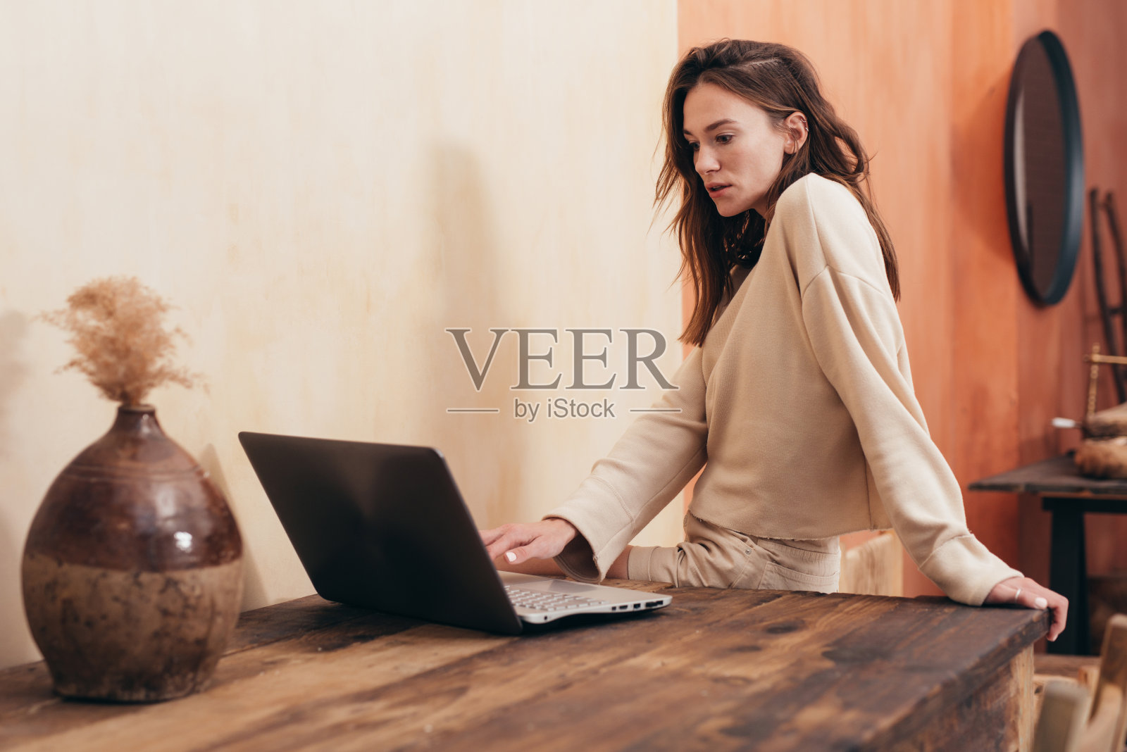 年轻女子站在桌前，拿着笔记本电脑照片摄影图片