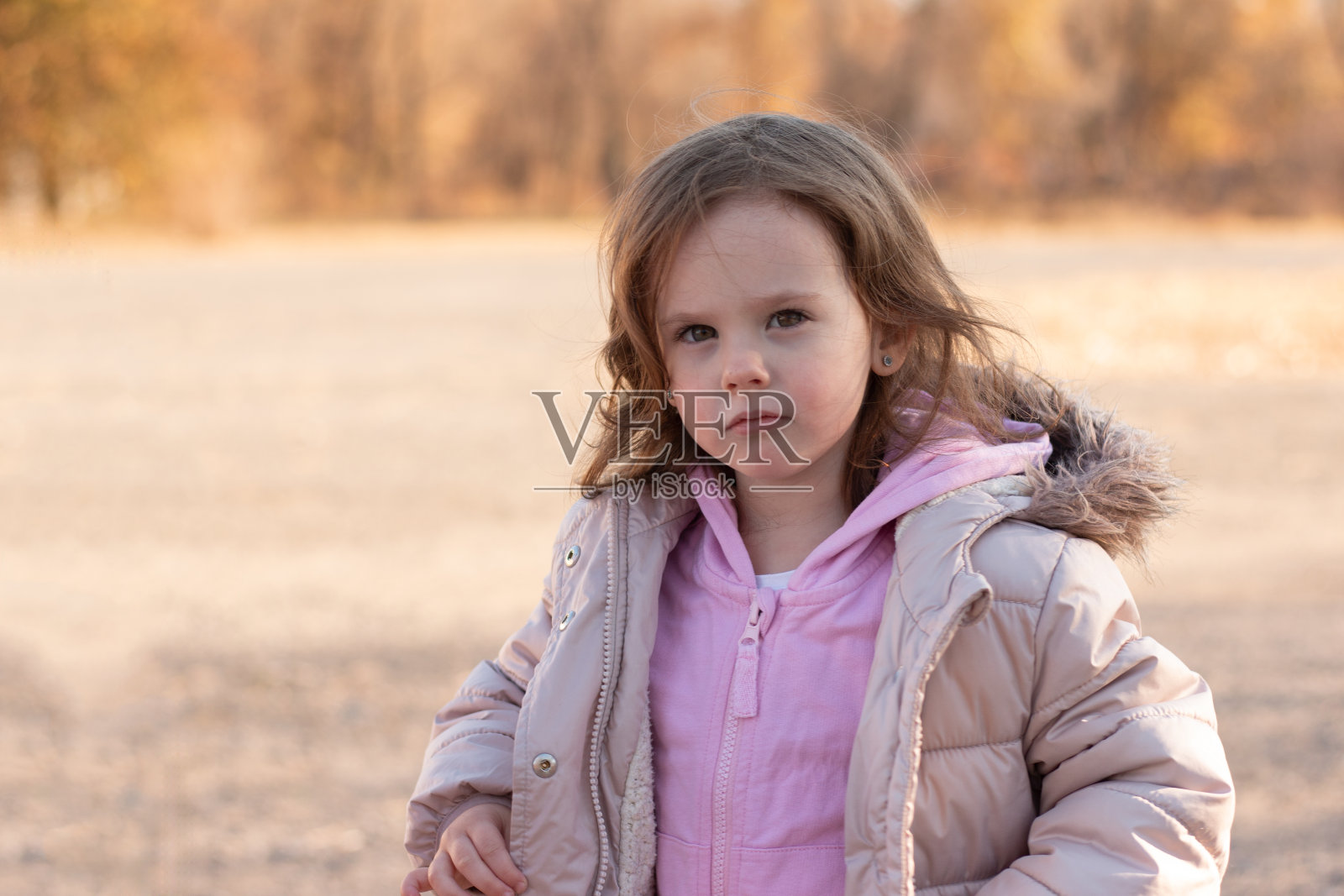 美丽的红头发小女孩，穿着夹克，戴着蓬松的兜帽，在秋天的街道上微笑照片摄影图片