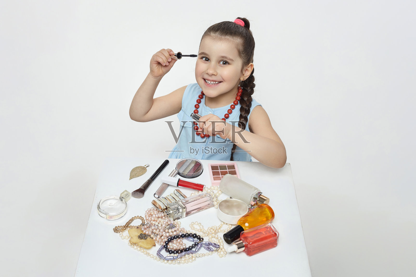 黑头发的小女孩在玩化妆。有趣的照片拍摄在工作室的白色背景照片摄影图片