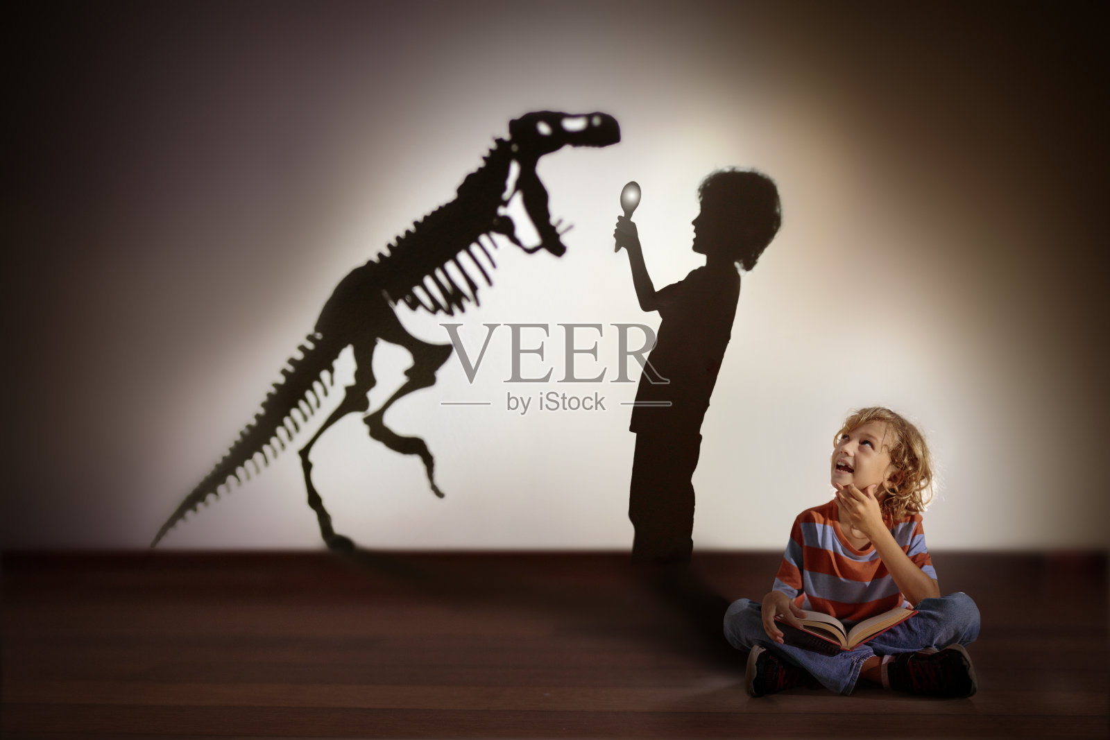 恐龙的影子在孩子的梦里。孩子们读,想象照片摄影图片