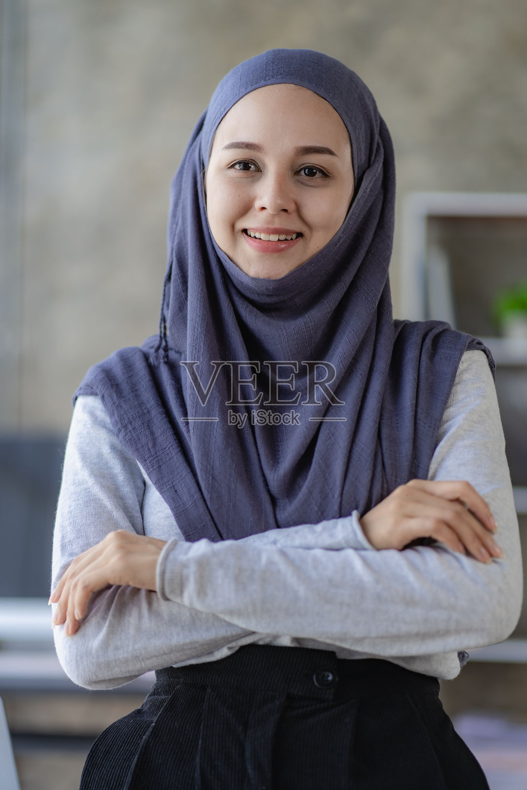 一位美丽的亚洲穆斯林妇女戴着头巾，在办公室自信地微笑着。照片摄影图片