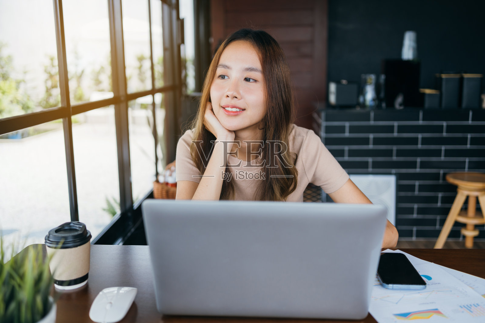 自由职业者亚洲女性微笑着她的工作与笔记本电脑和智能手机的工作工作在工作空间。拥有自由生活方式理念的小型企业。照片摄影图片