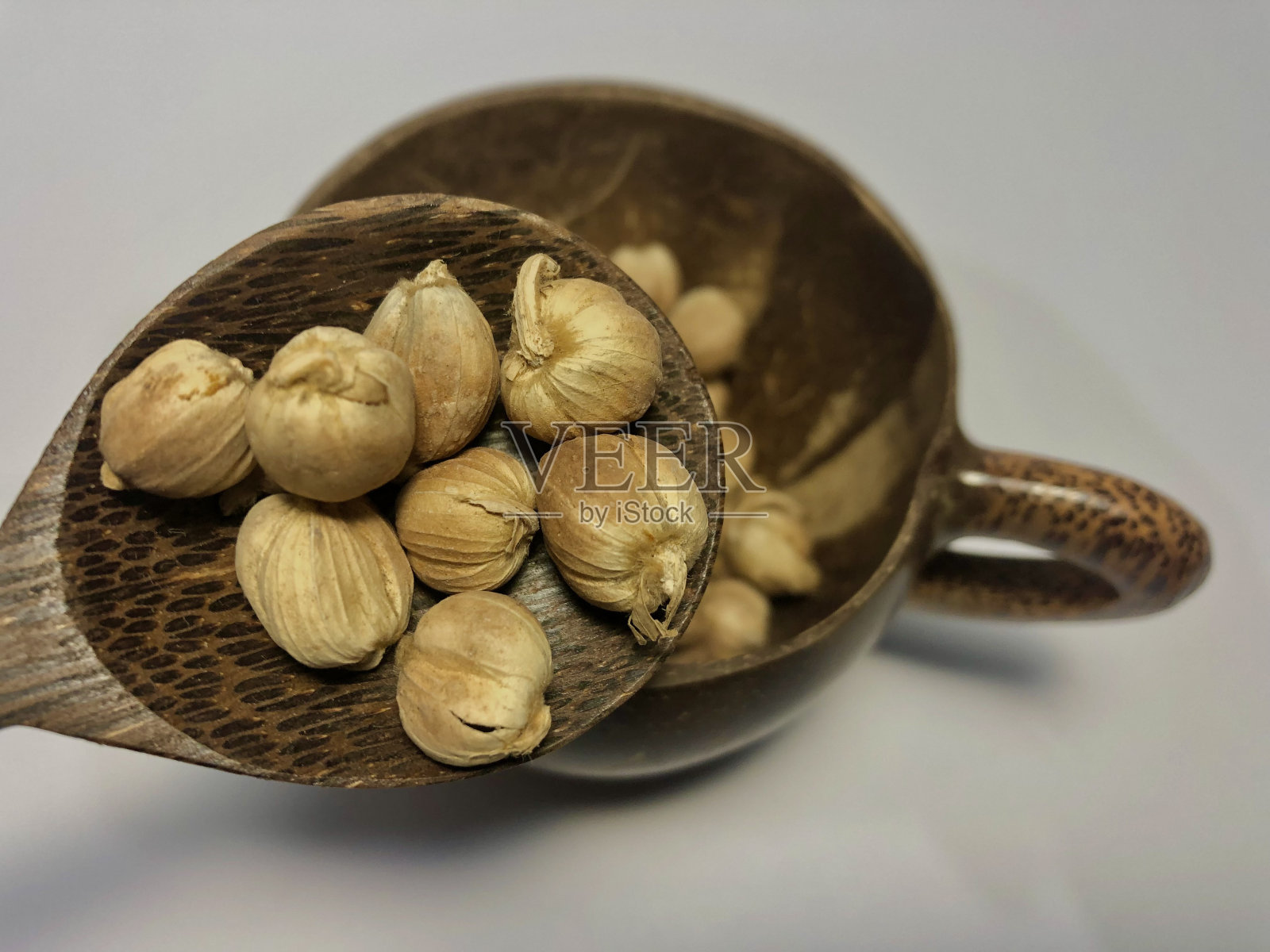 小豆蔻放在勺子和木杯上照片摄影图片