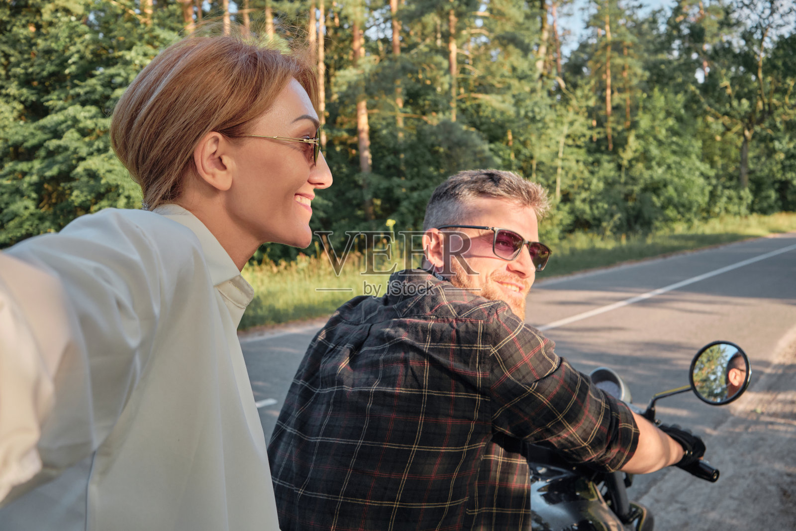 一对中年夫妇骑着摩托车玩得很开心，还在自拍照片摄影图片