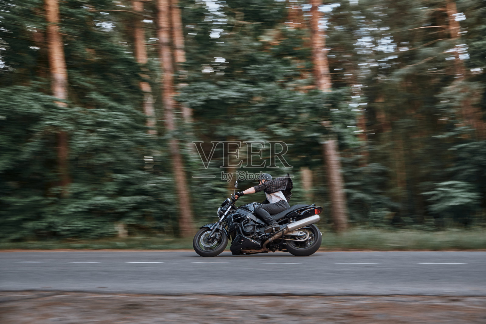 一个戴着头盔的年轻男子骑着自行车在森林的道路上快速高速行驶照片摄影图片