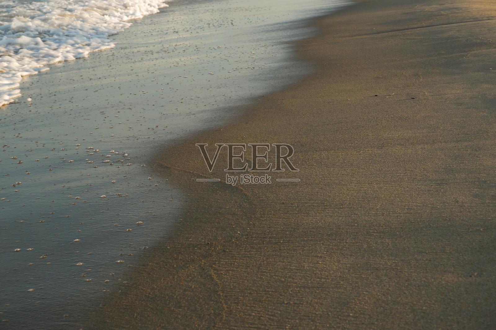 自然背景。沙子的表面被来袭的海浪冲刷掉了。照片摄影图片