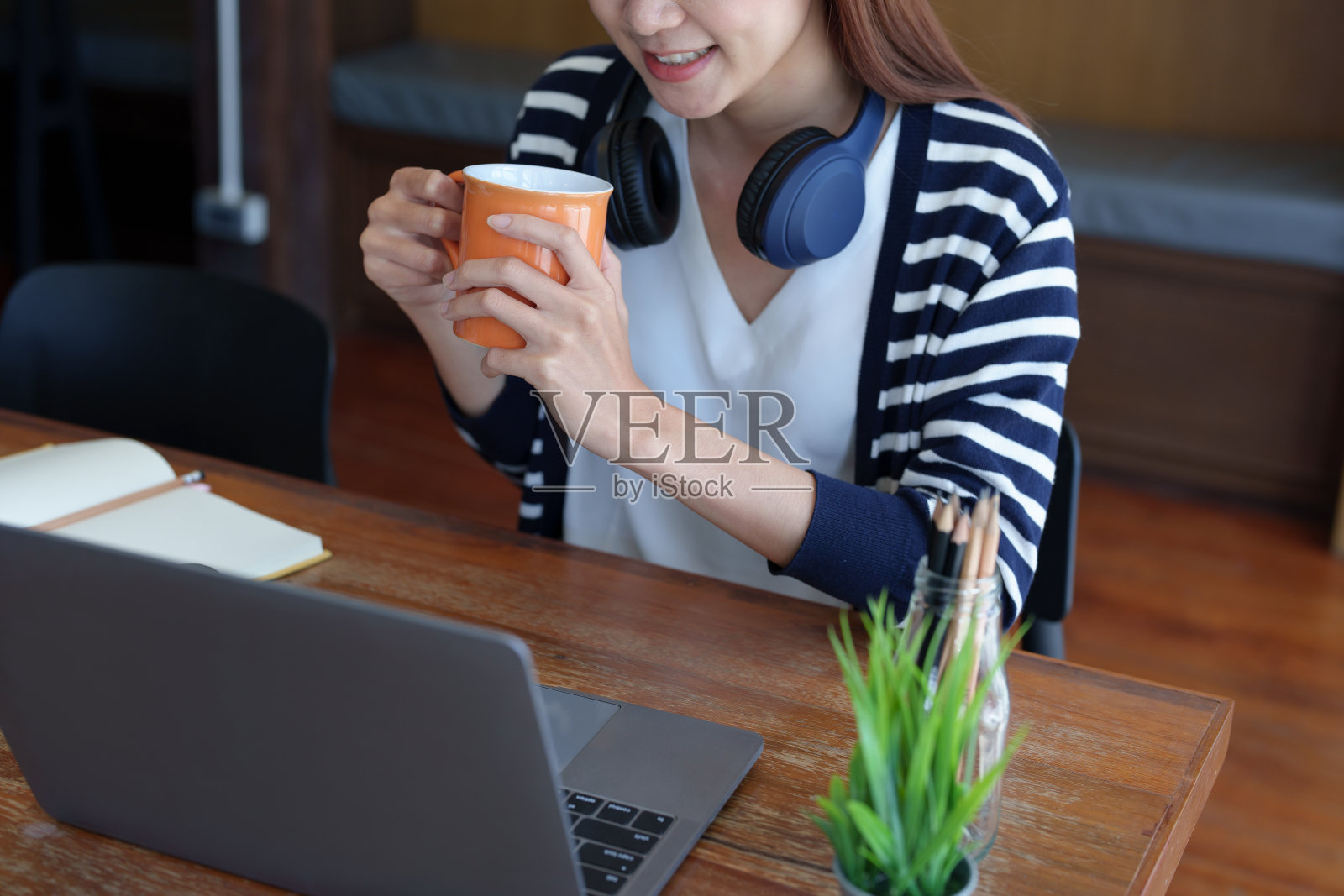 画像的年轻，迷人的亚洲少女使用电脑和喝咖啡，同时在线学习，在图书馆的早上照片摄影图片