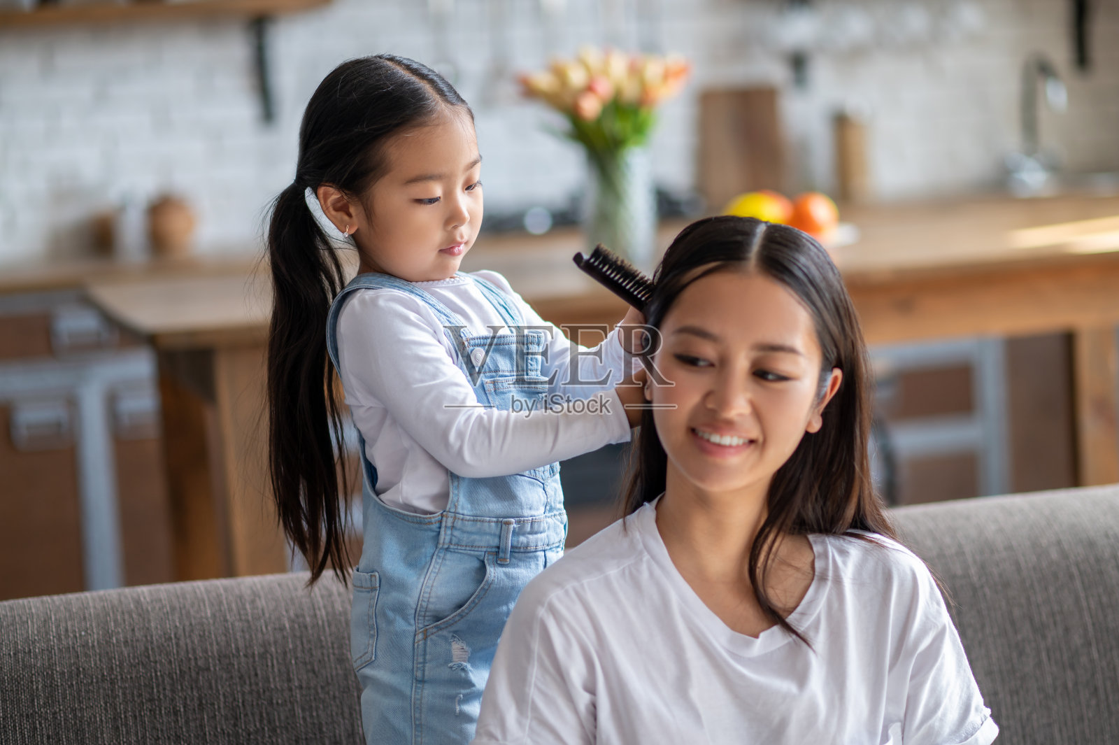 体贴的女儿用梳子梳理她的女性父母的头发照片摄影图片