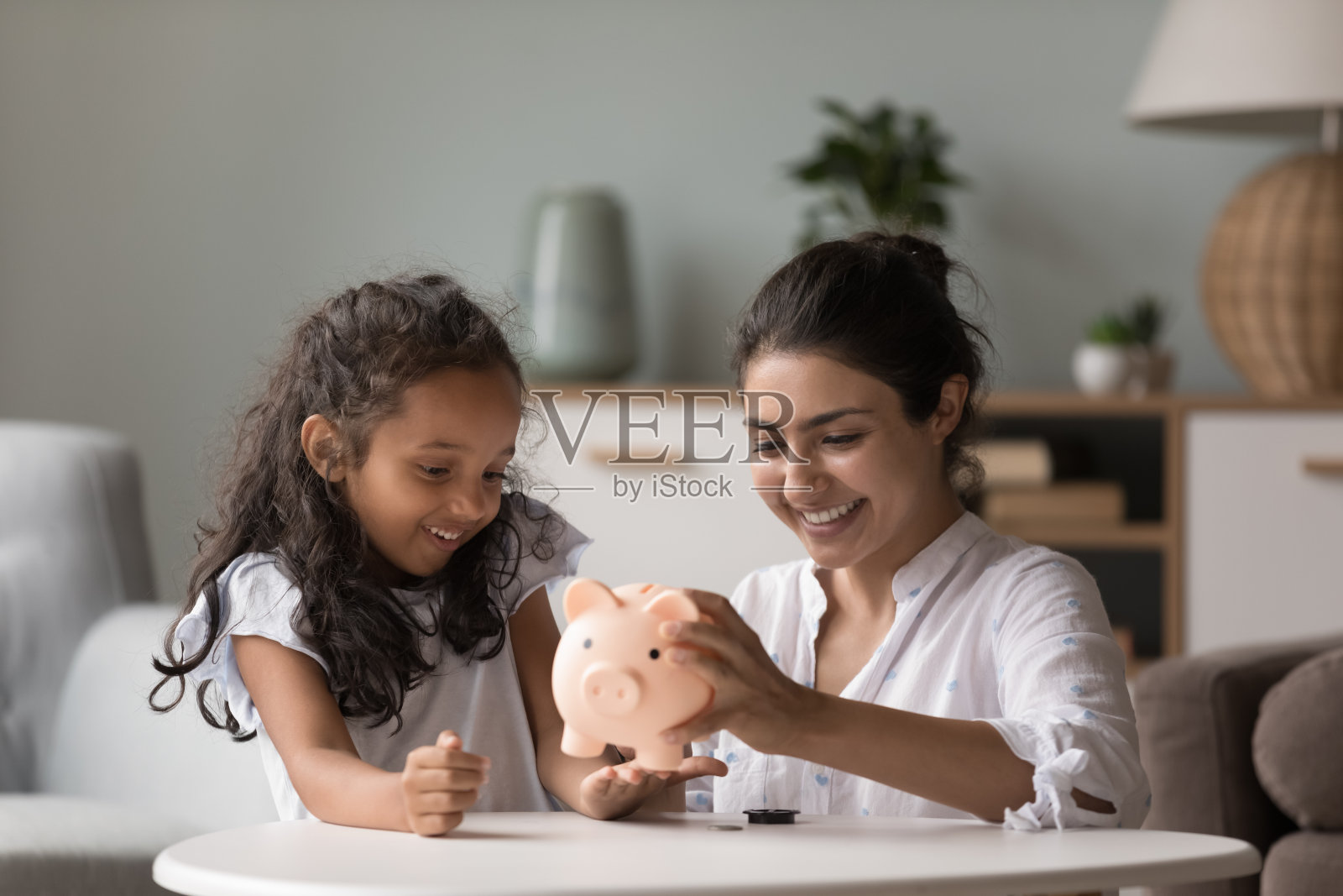 印度妇女和女儿从储蓄罐中取出钱照片摄影图片