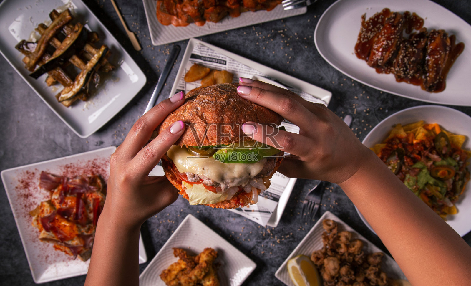 女人的手拿着美味的美国汉堡和炸薯条在餐厅的桌子上。平的。俯视图照片摄影图片