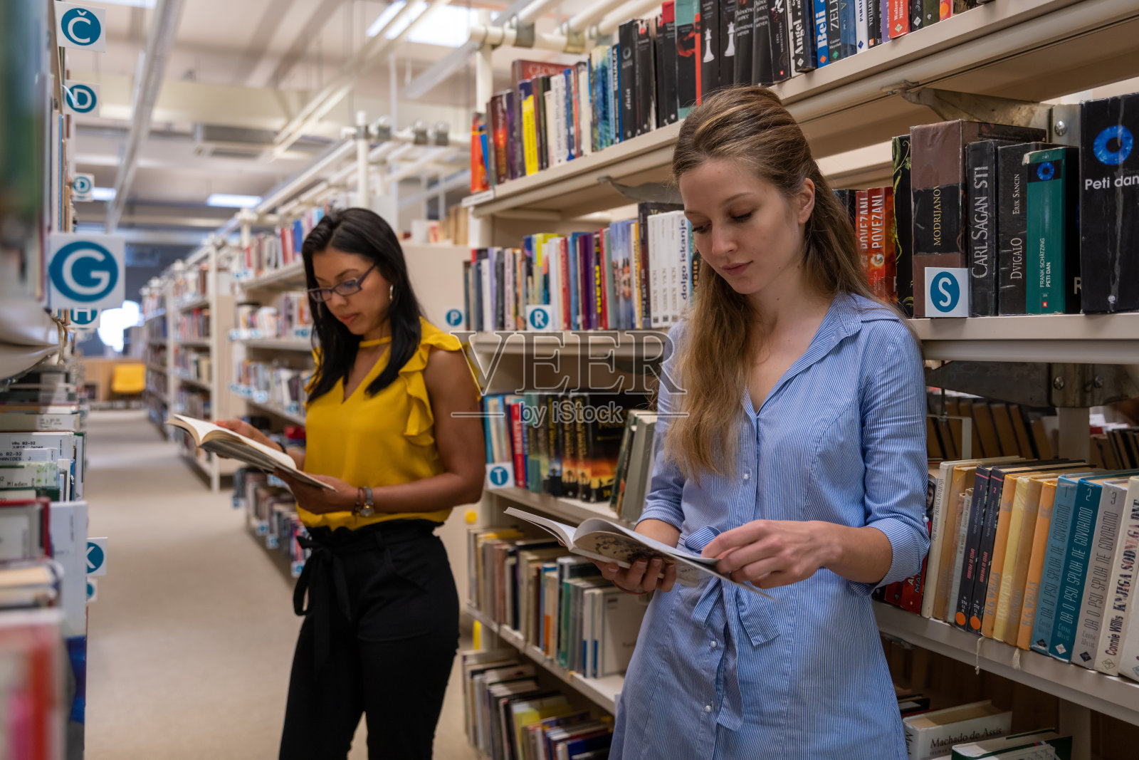 读者翻阅书架上的书。照片摄影图片
