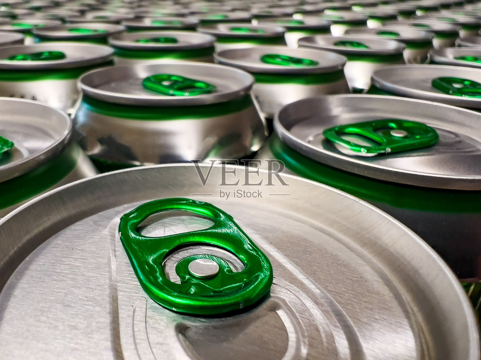 一堆顶部是绿色的银色啤酒罐的特写镜头照片摄影图片