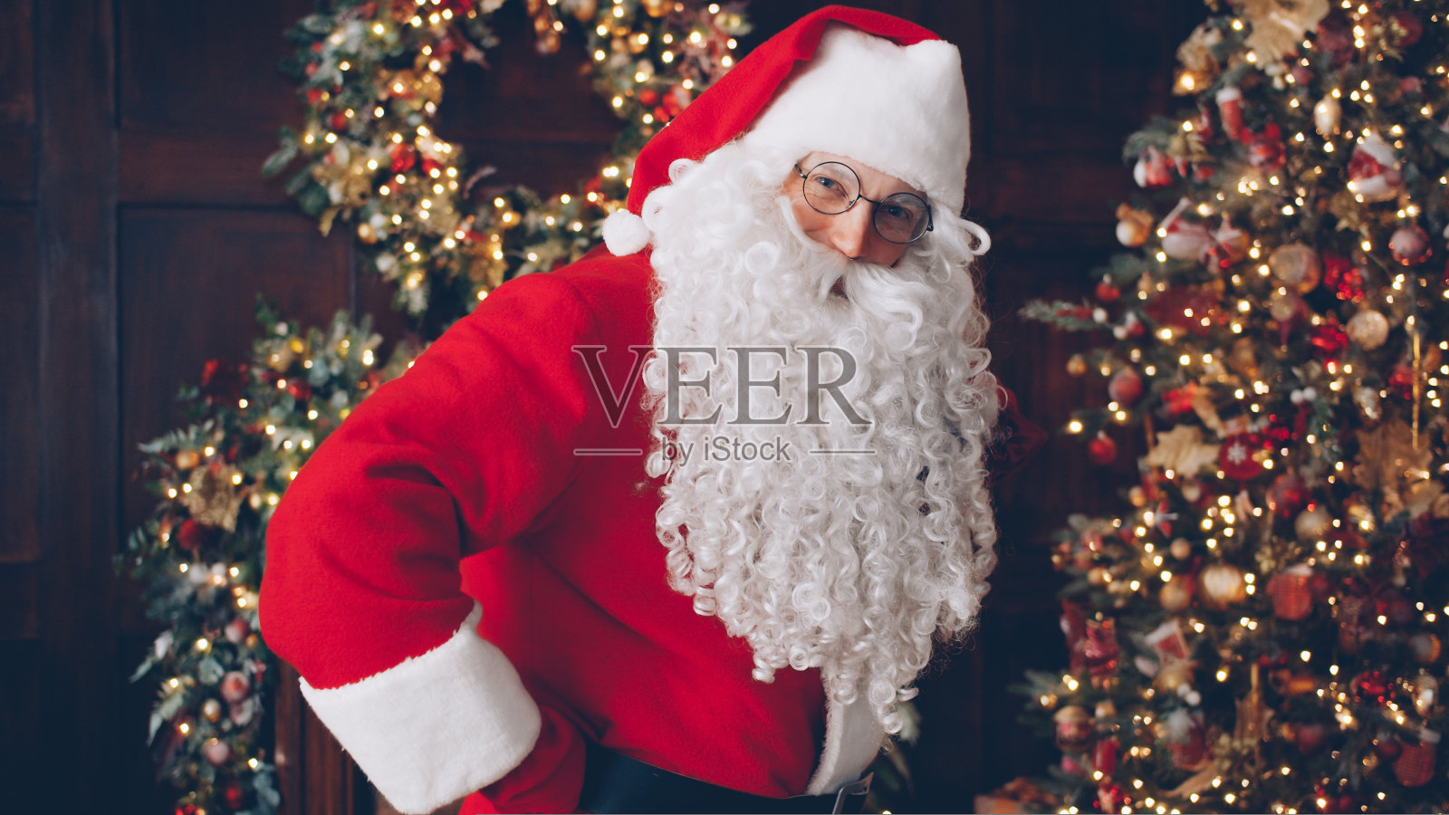圣诞老人的画像拿着礼物袋在圣诞树附近装饰的房子照片摄影图片
