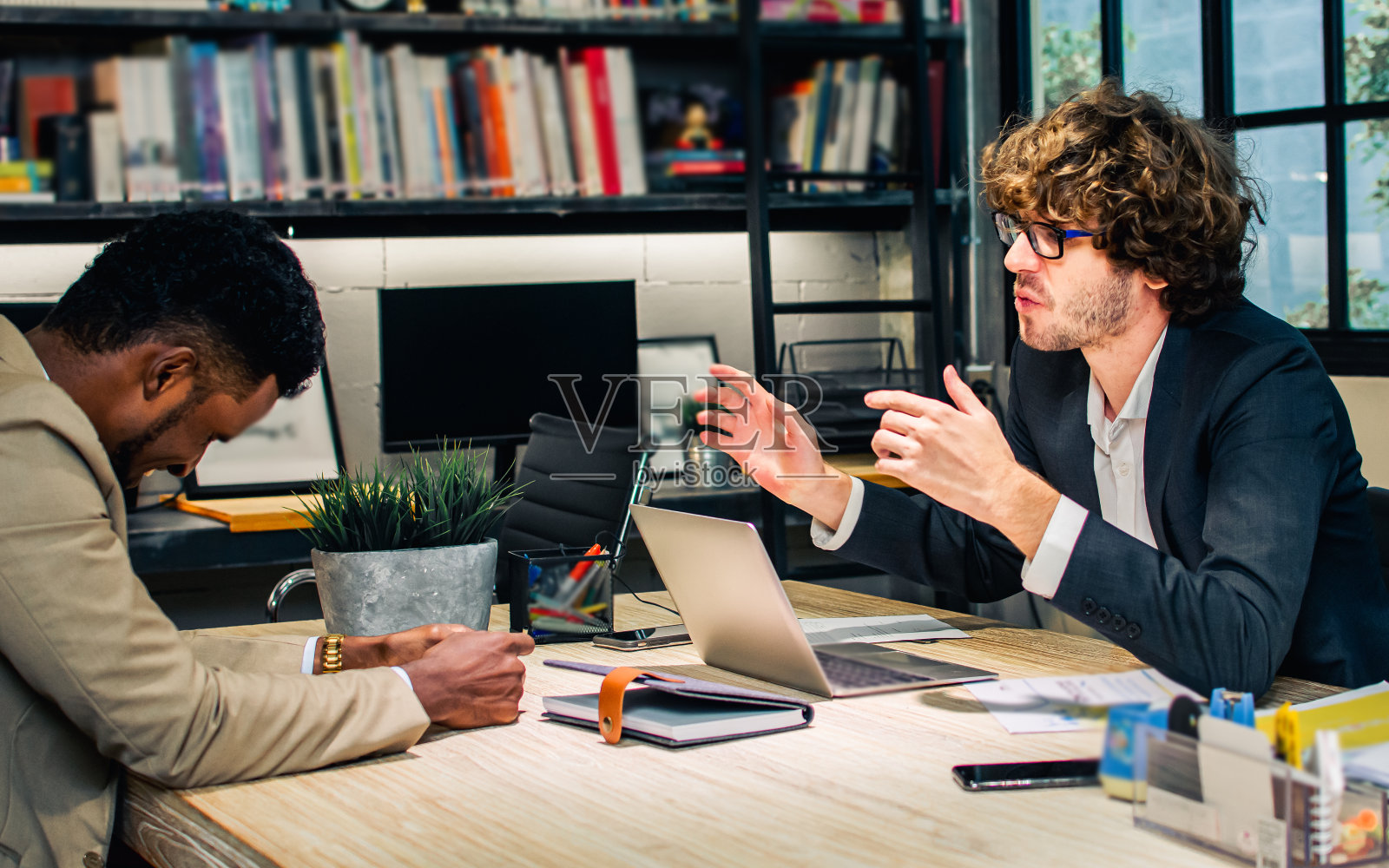 两个不同肤色的白人和非洲商人认真地讨论着，争论着，坐在办公室现代化的会议室里。他们对这个项目的想法不满意，不同意。照片摄影图片