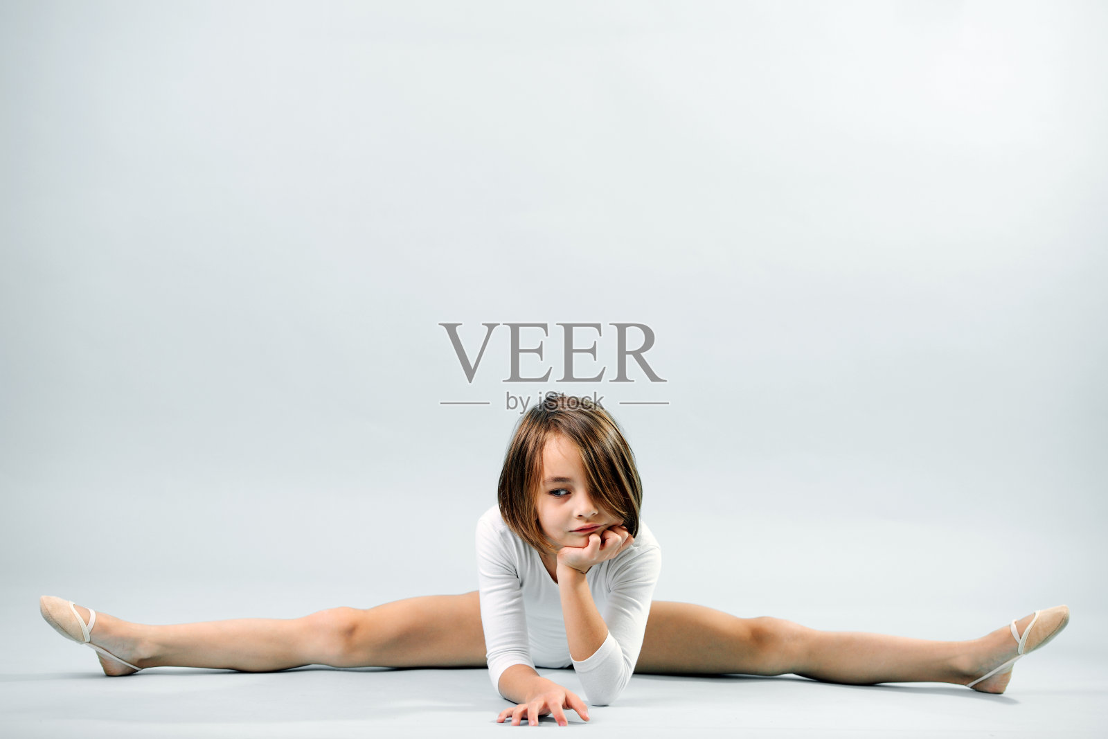 看着一旁无聊的小女孩穿着白色紧身衣坐在劈叉照片摄影图片