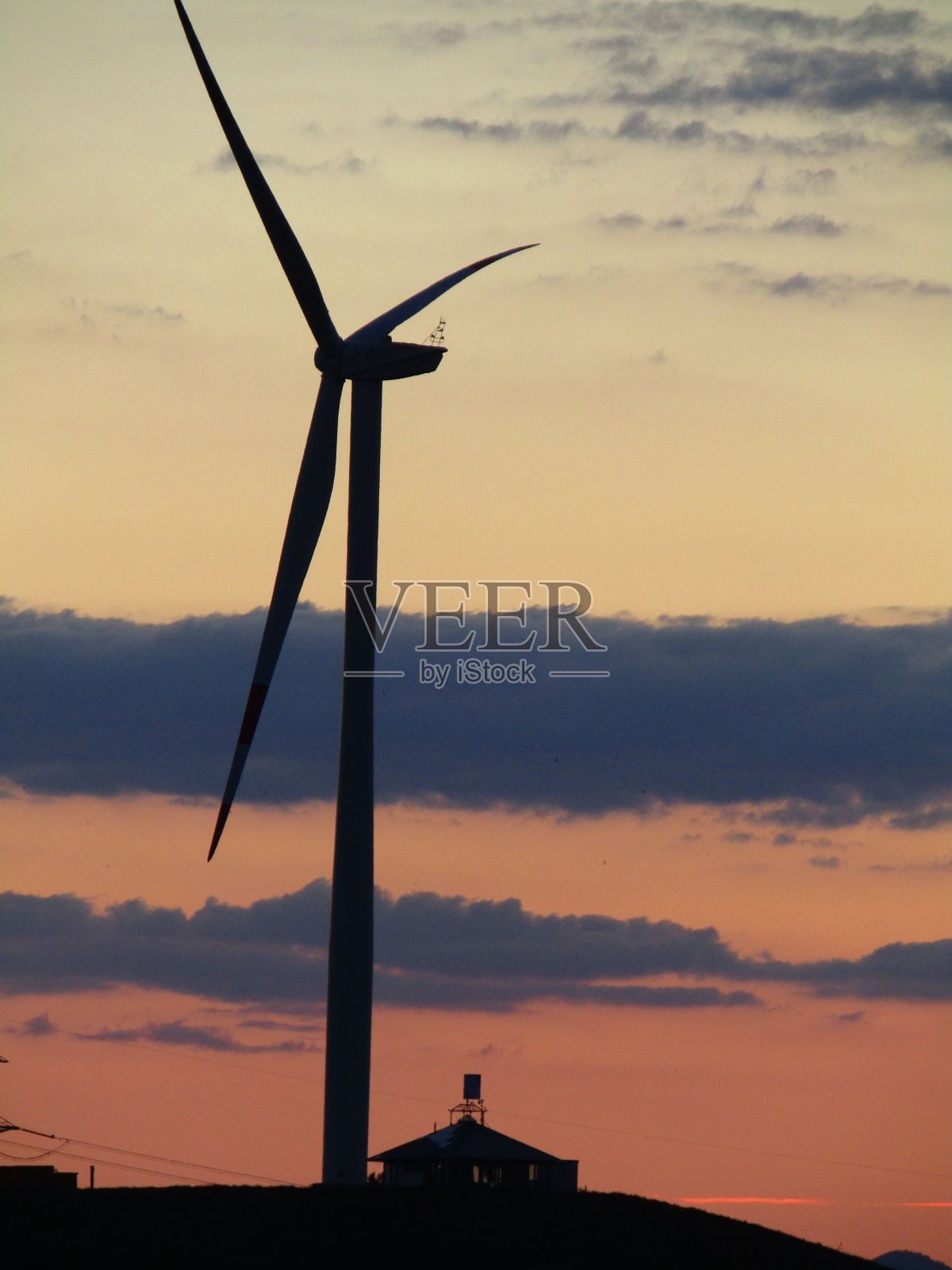 日落时在多云的天空下拍摄的风力涡轮机特写照片摄影图片
