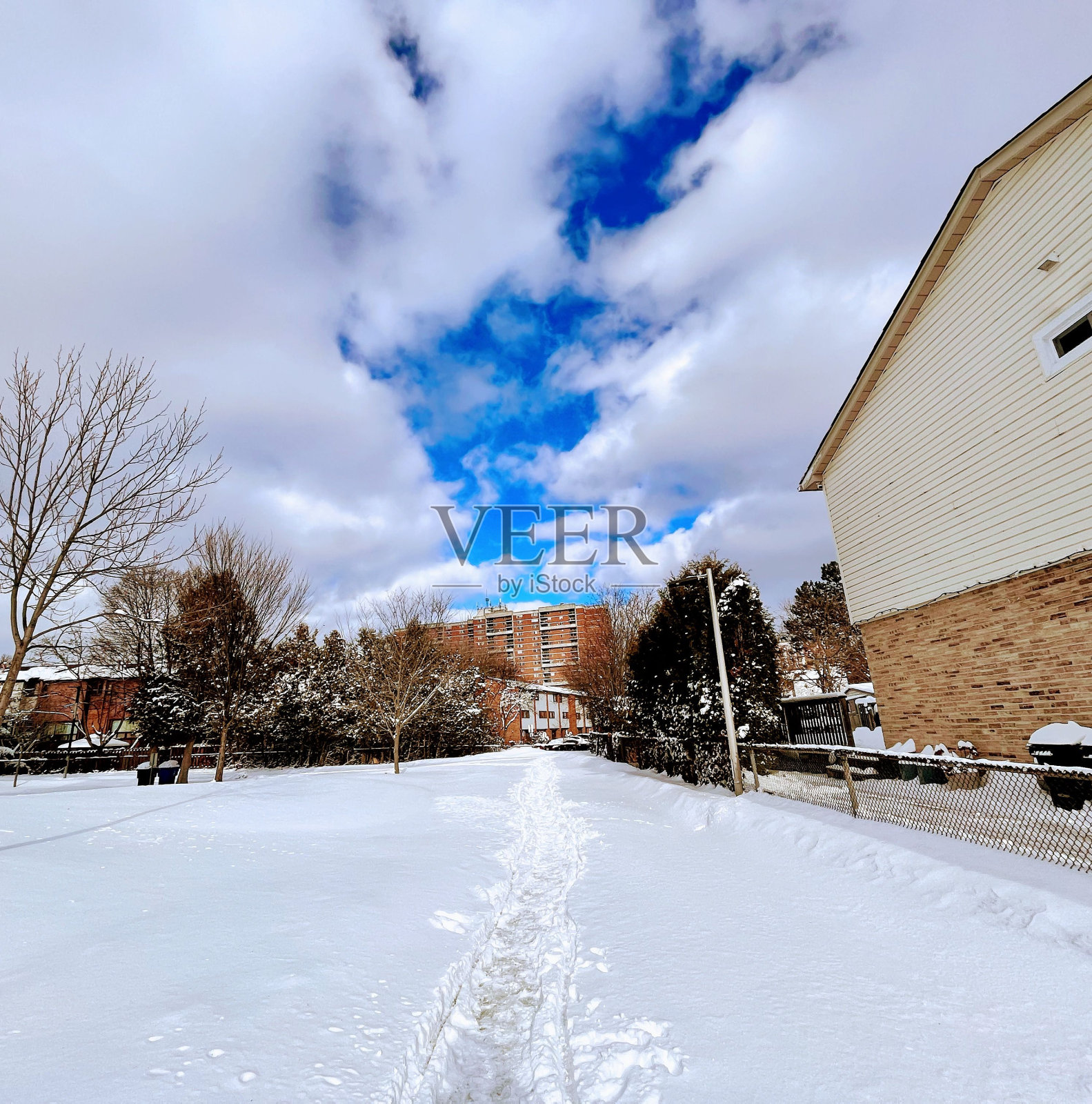 在多云的天空下，建筑被雪覆盖的住宅区照片摄影图片