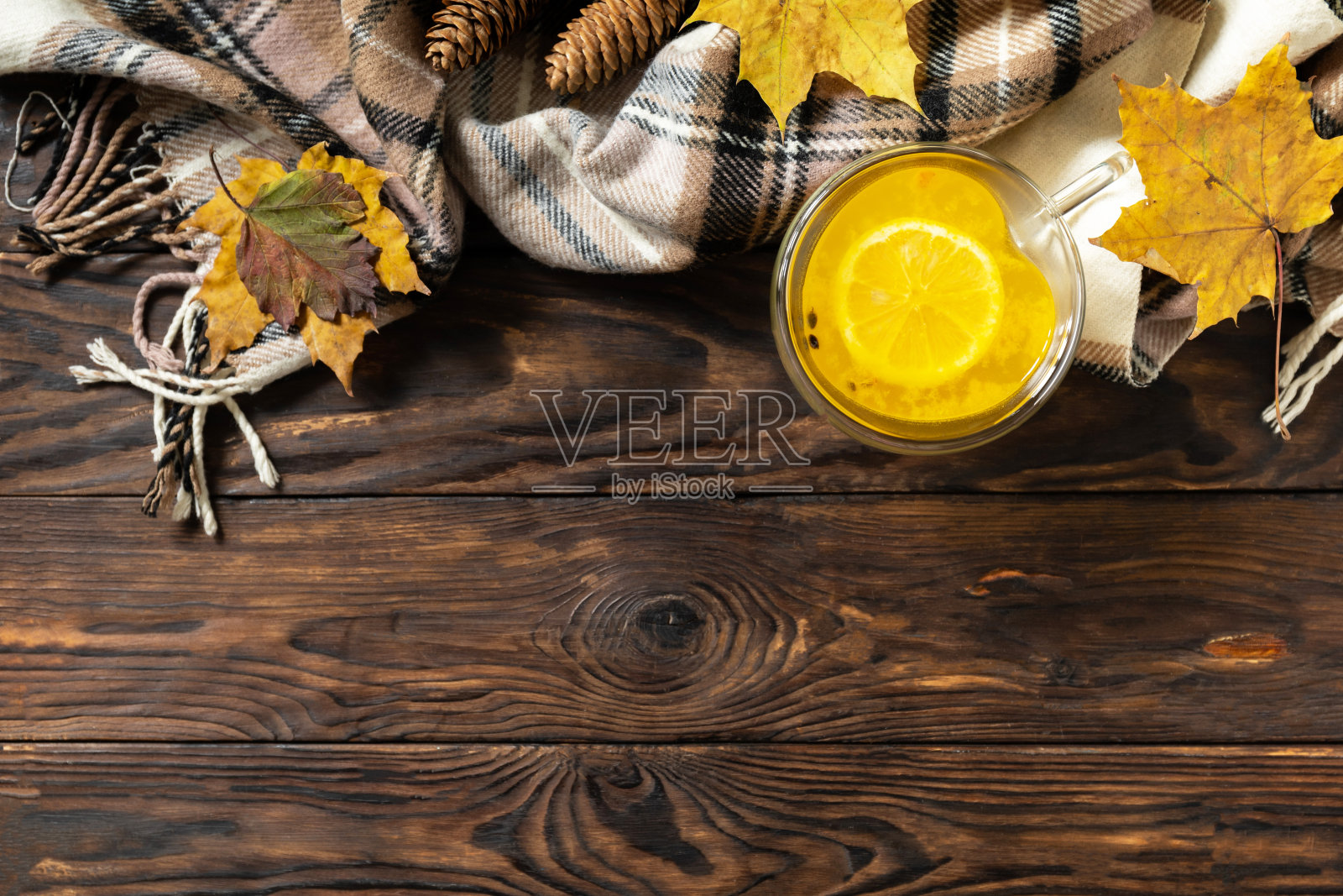 季节性的秋季概念与饮料。一杯热海â 'â 'â 'â '鼠李茶配柠檬，温暖的围巾和枫叶在乡村的背景，创造性的平铺。从以上观点。副本的空间。照片摄影图片
