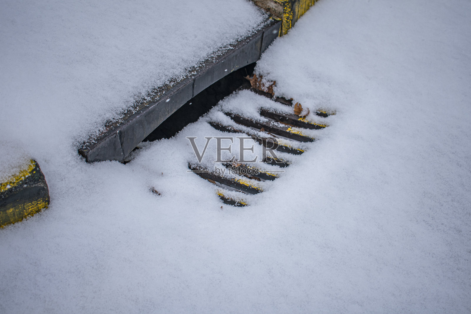 高角度拍摄的下水道笼完全覆盖在沥青雪照片摄影图片