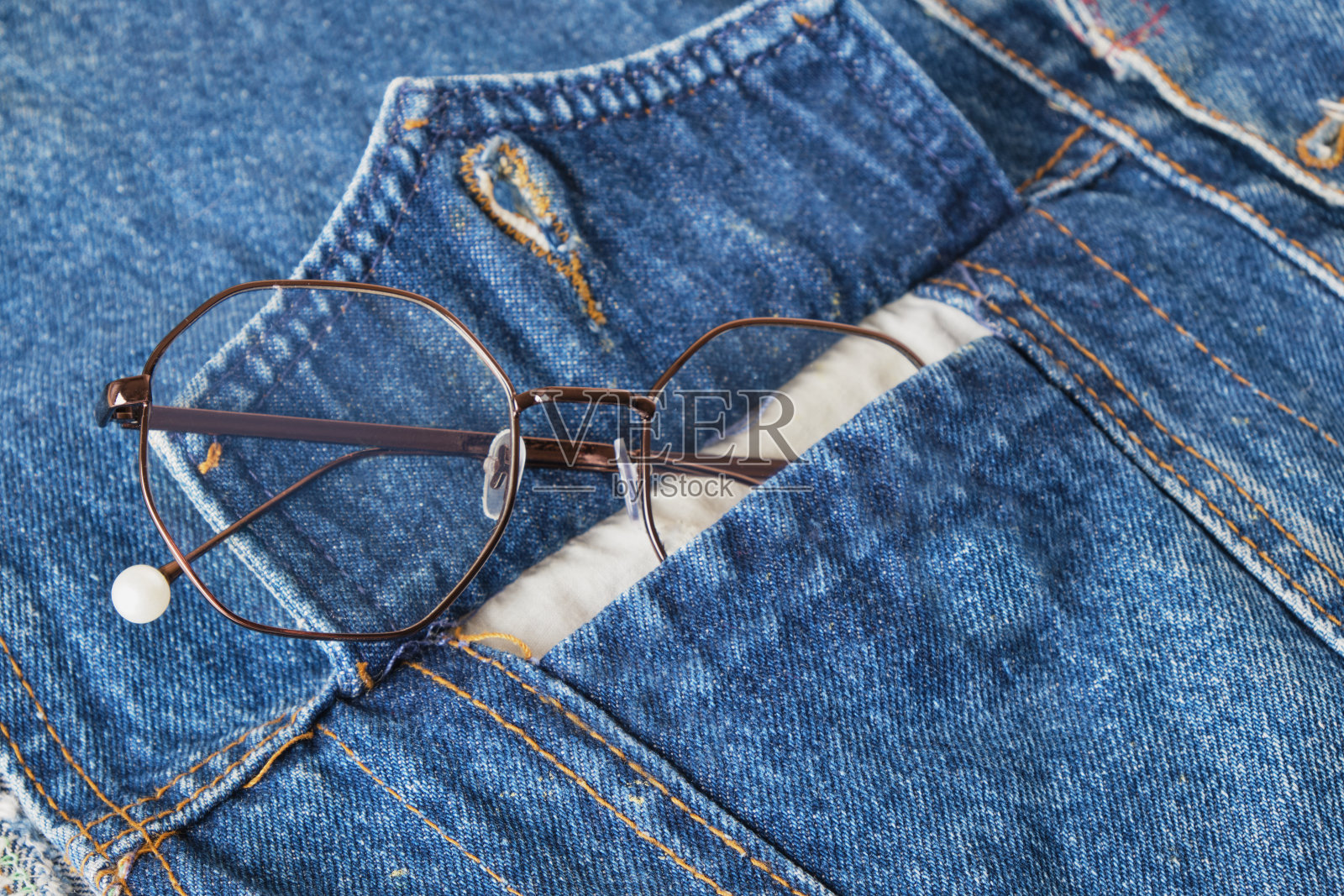 蓝色牛仔背心口袋里的眼镜照片摄影图片