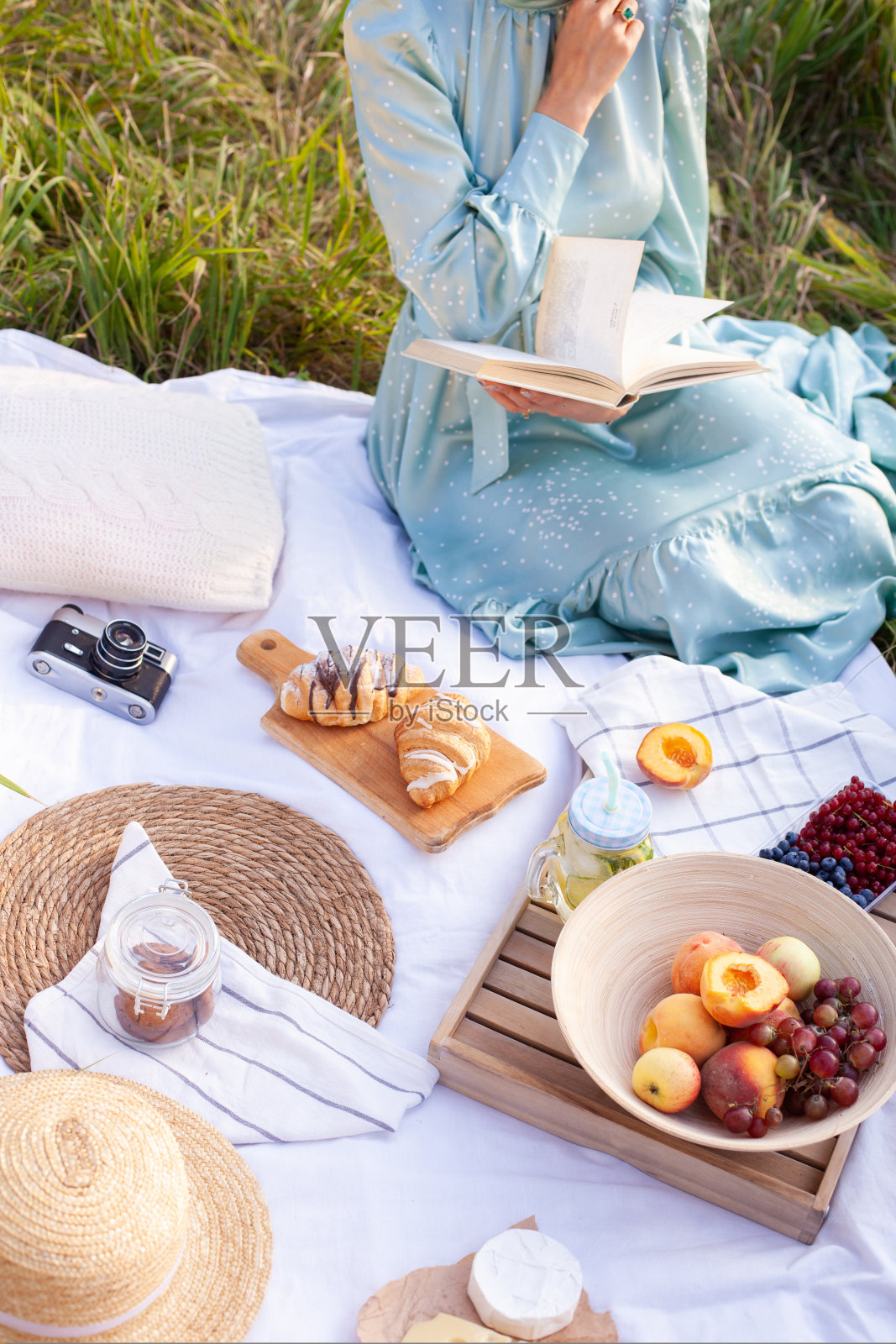 一名身穿蓝色连衣裙的女子坐在公园里野餐，全景尽收眼底照片摄影图片