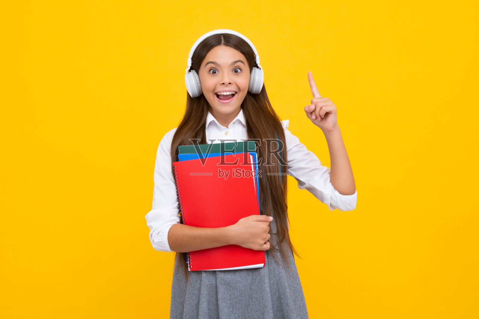 女学生与副本在孤立的背景上摆姿势。文法学校的文学课。智力儿童读者。十几岁女孩兴奋的面容，欢快的情绪。照片摄影图片
