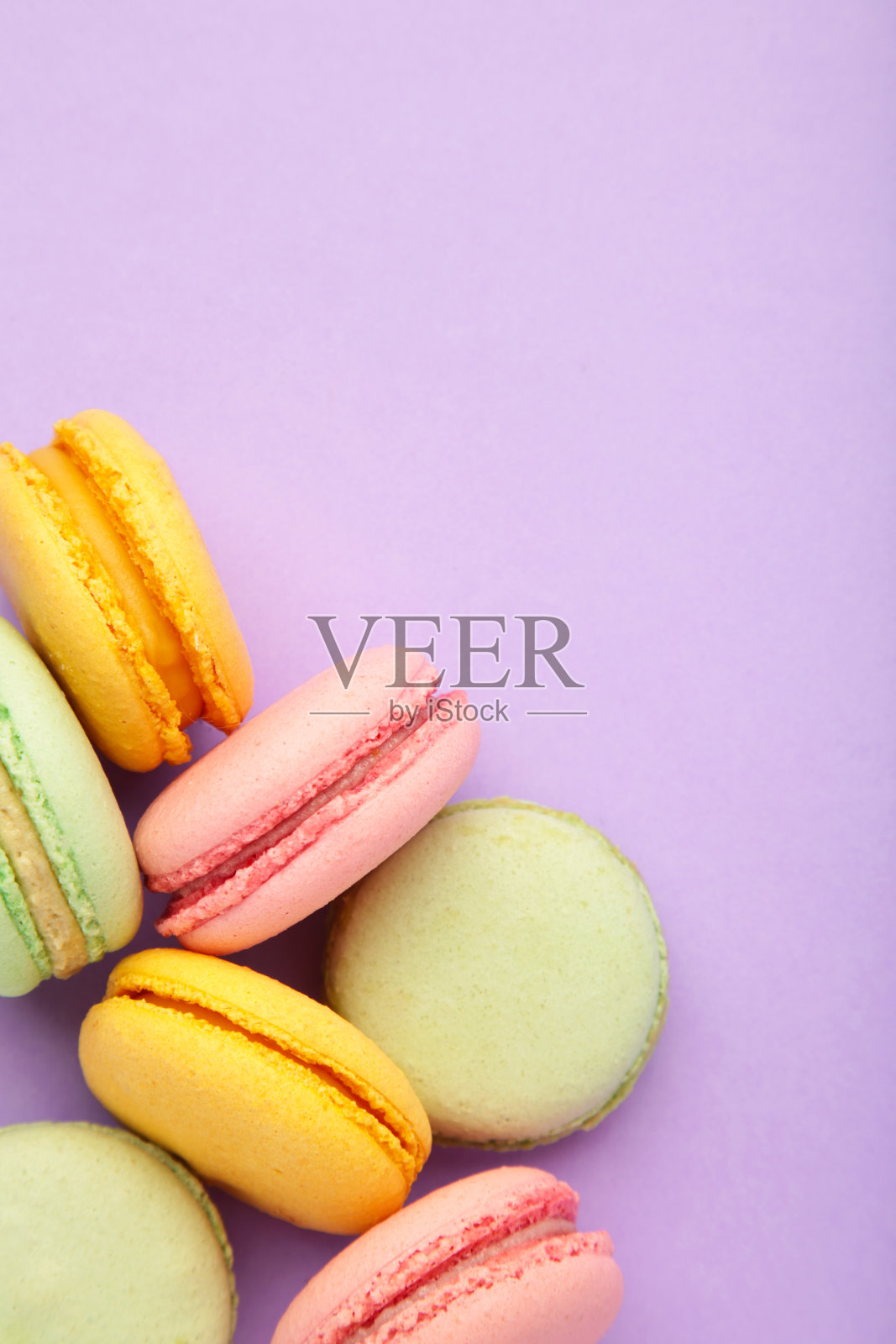 紫色背景的马卡龙。甜的甜点。垂直图照片摄影图片