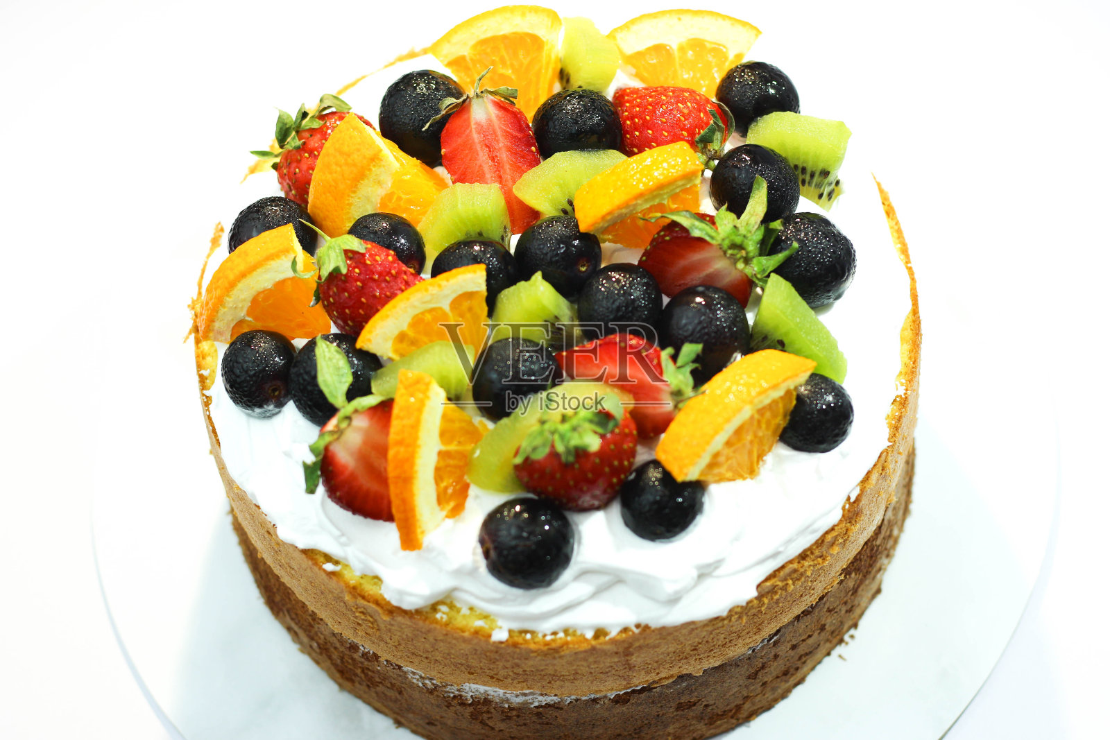 自制的特雷斯leches蛋糕，配有蛋白糖霜和新鲜葡萄、猕猴桃、草莓和橙子，放在白色盘子里。水果蛋糕孤立在白色。食物concpet背景。照片摄影图片