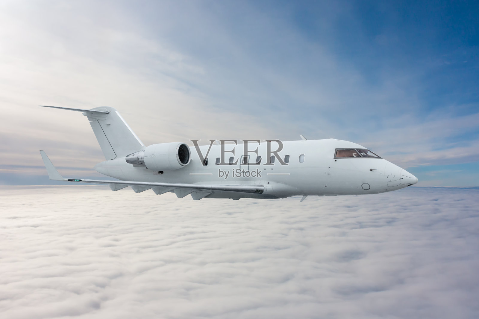 白色的私人飞机在云层上空飞行照片摄影图片