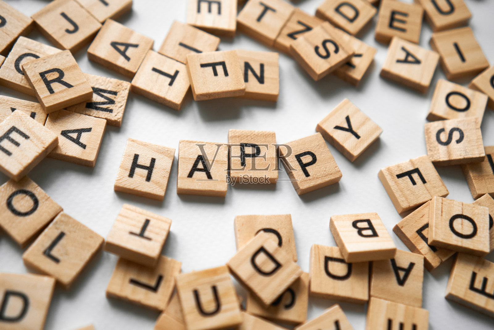 单词happy在白色浅灰色背景的中间用木块拼写。有许多周围有字母的方形木块。问候祝福卡。高质量水平照片照片摄影图片