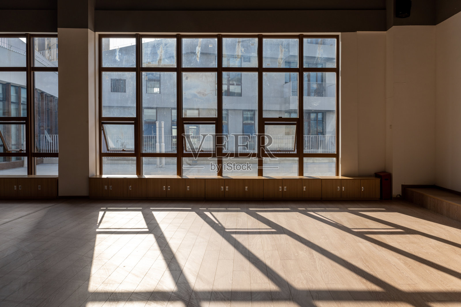 阳光透过窗户在空荡荡的多媒体教室的木纹地板上产生的光影照片摄影图片