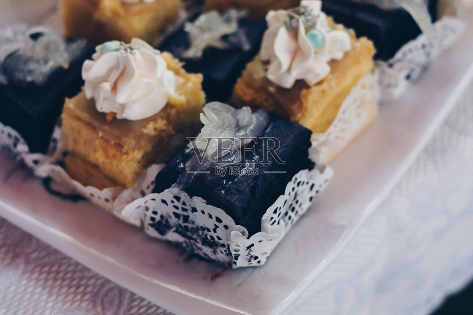 片奶油美味的紫色山药，又名ube蛋糕与macapuno又名椰子运动和柠檬蛋奶蛋糕在白色亚麻布覆盖的桌子上照片摄影图片