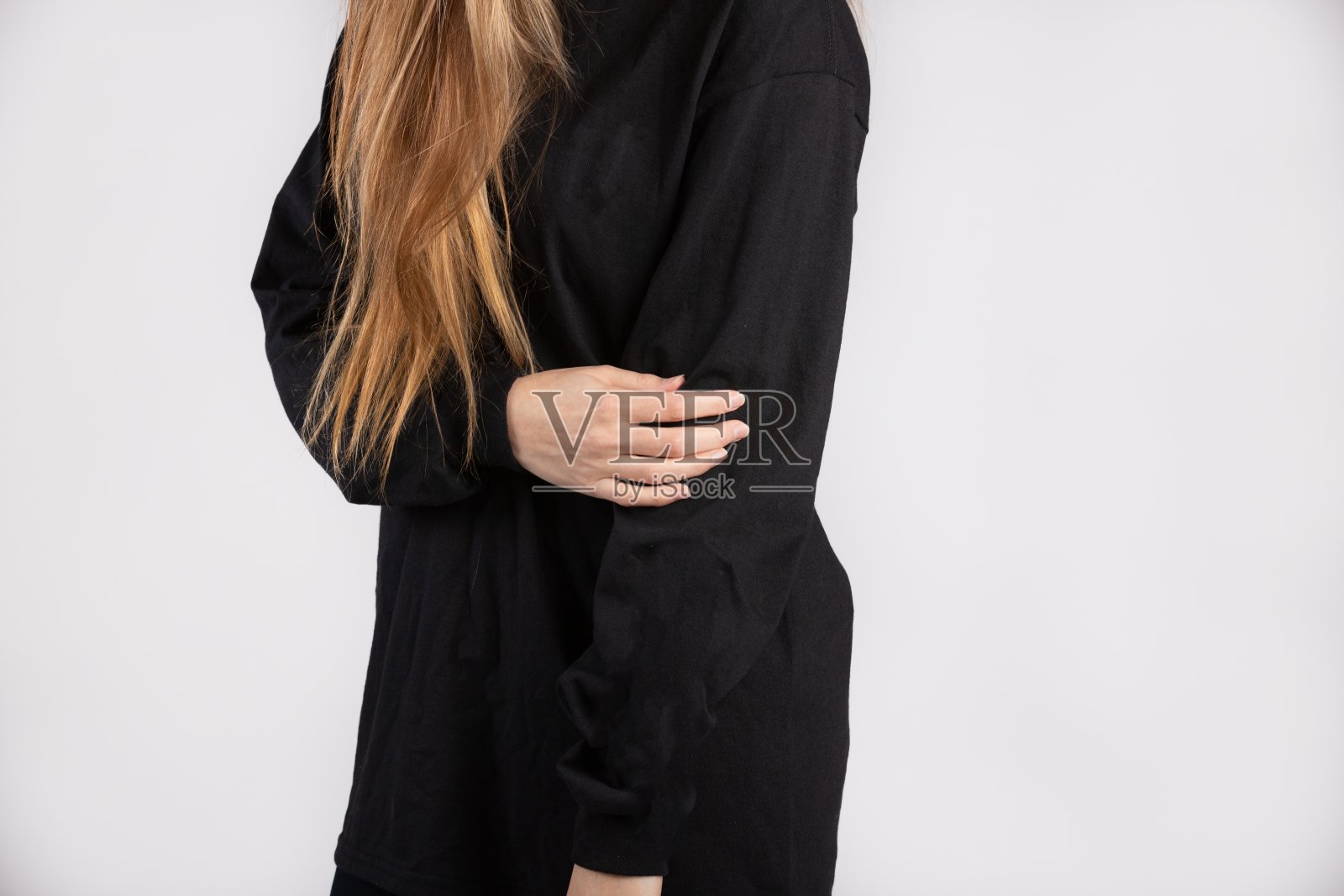 身穿黑色长袖t恤的年轻女子靠白墙站着照片摄影图片