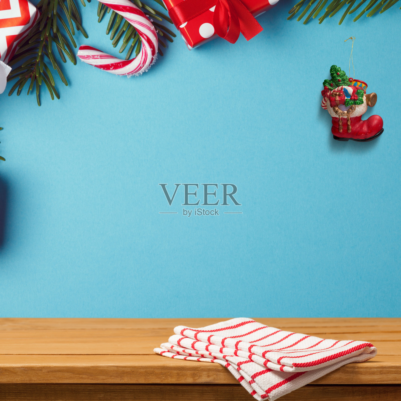 木制的桌子靠在蓝色的墙上，墙上装饰着圣诞装饰品照片摄影图片