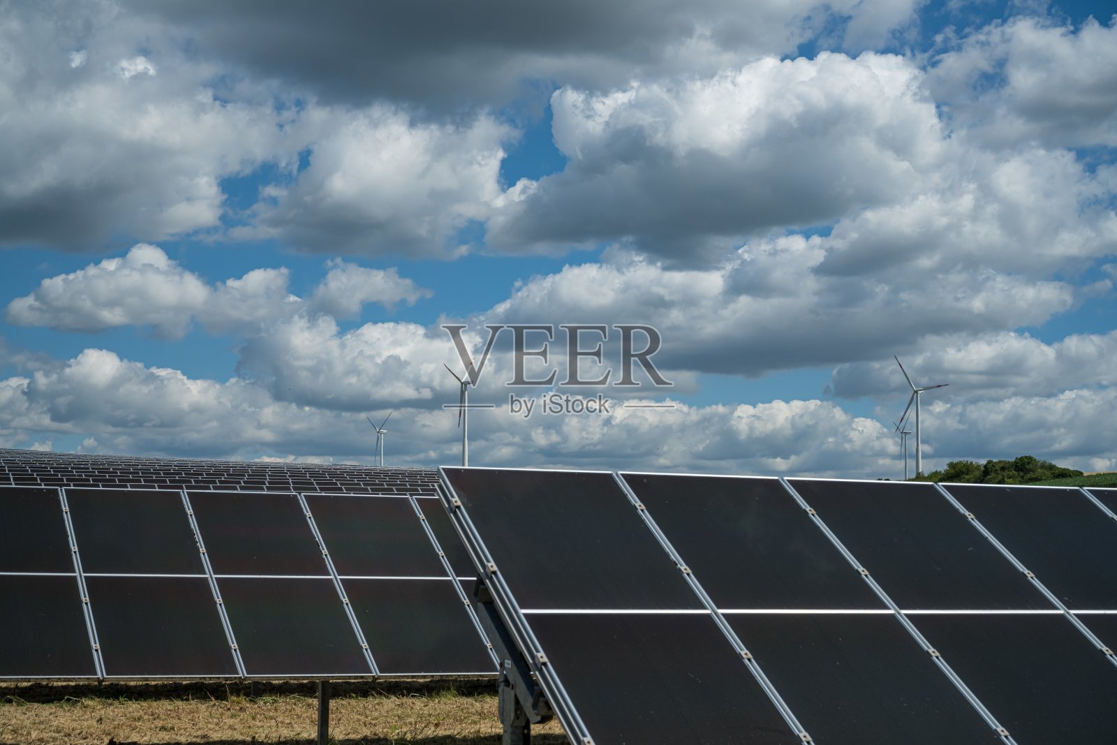 使用可再生能源的太阳能电池板在布满云层的天空下的田野上照片摄影图片