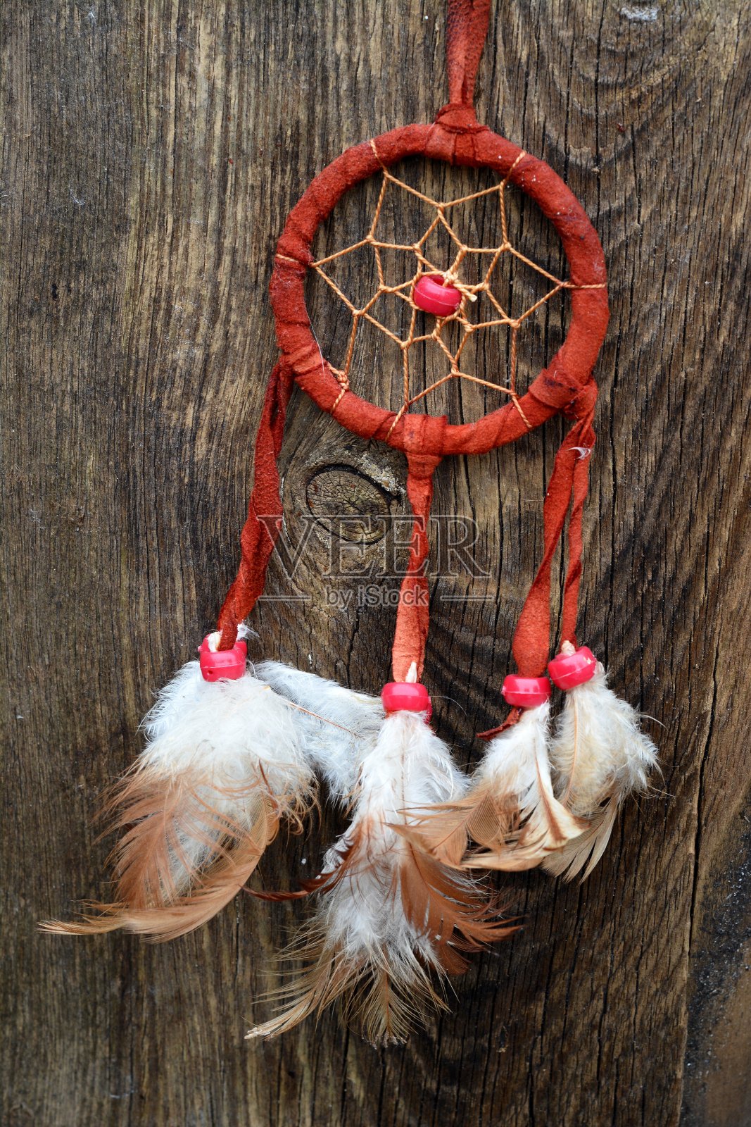 垂直拍摄的红色捕梦网挂在一个木头表面下的灯光照片摄影图片