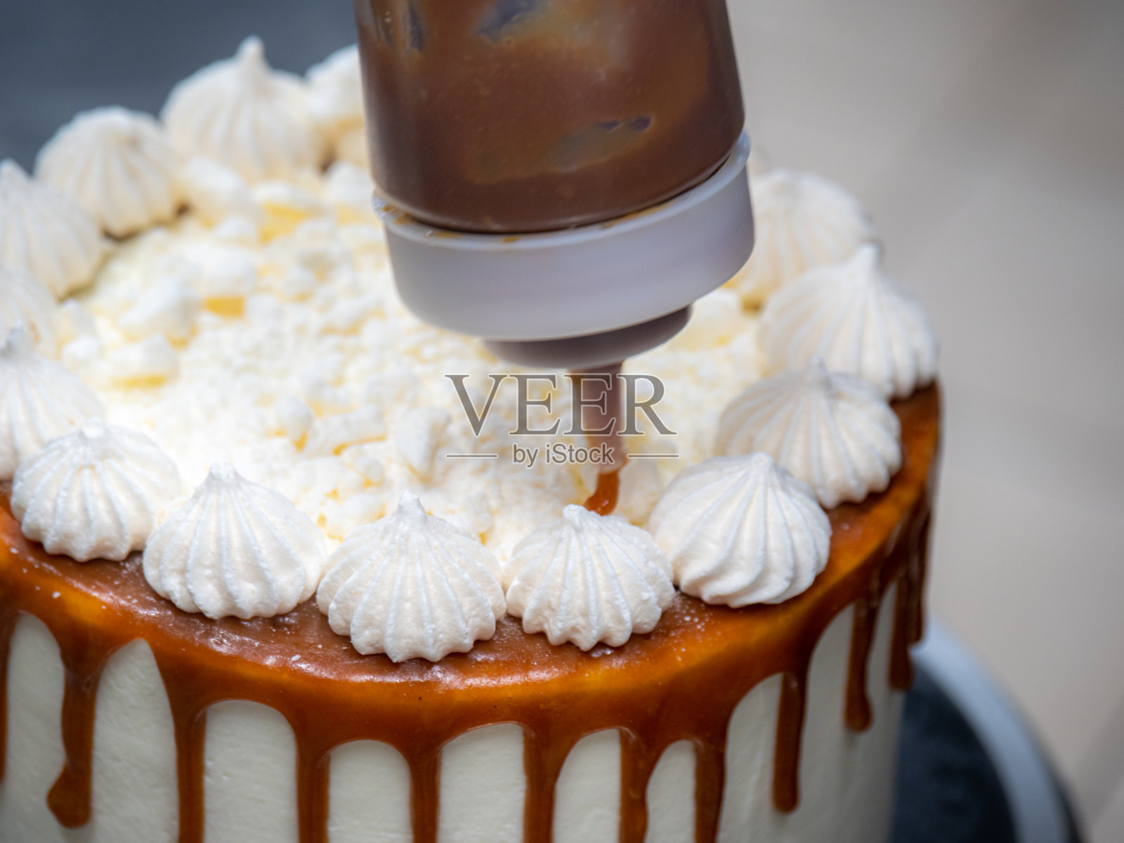 厨师手工制作蛋糕顶部的蛋白糖霜上滴着咸焦糖照片摄影图片