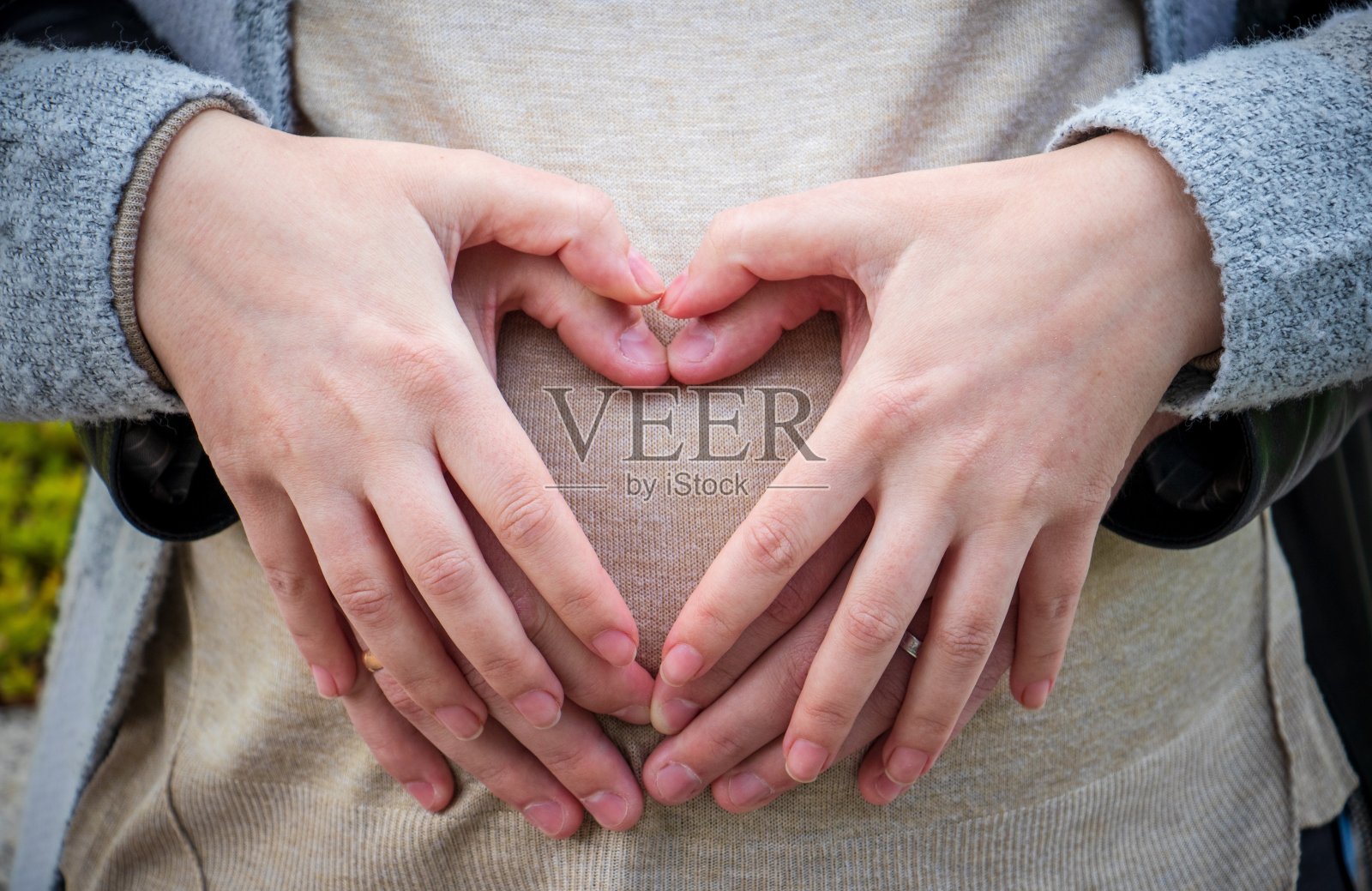 父母用手在怀孕女性的腹部上形成一个心形的特写——父母概念照片摄影图片
