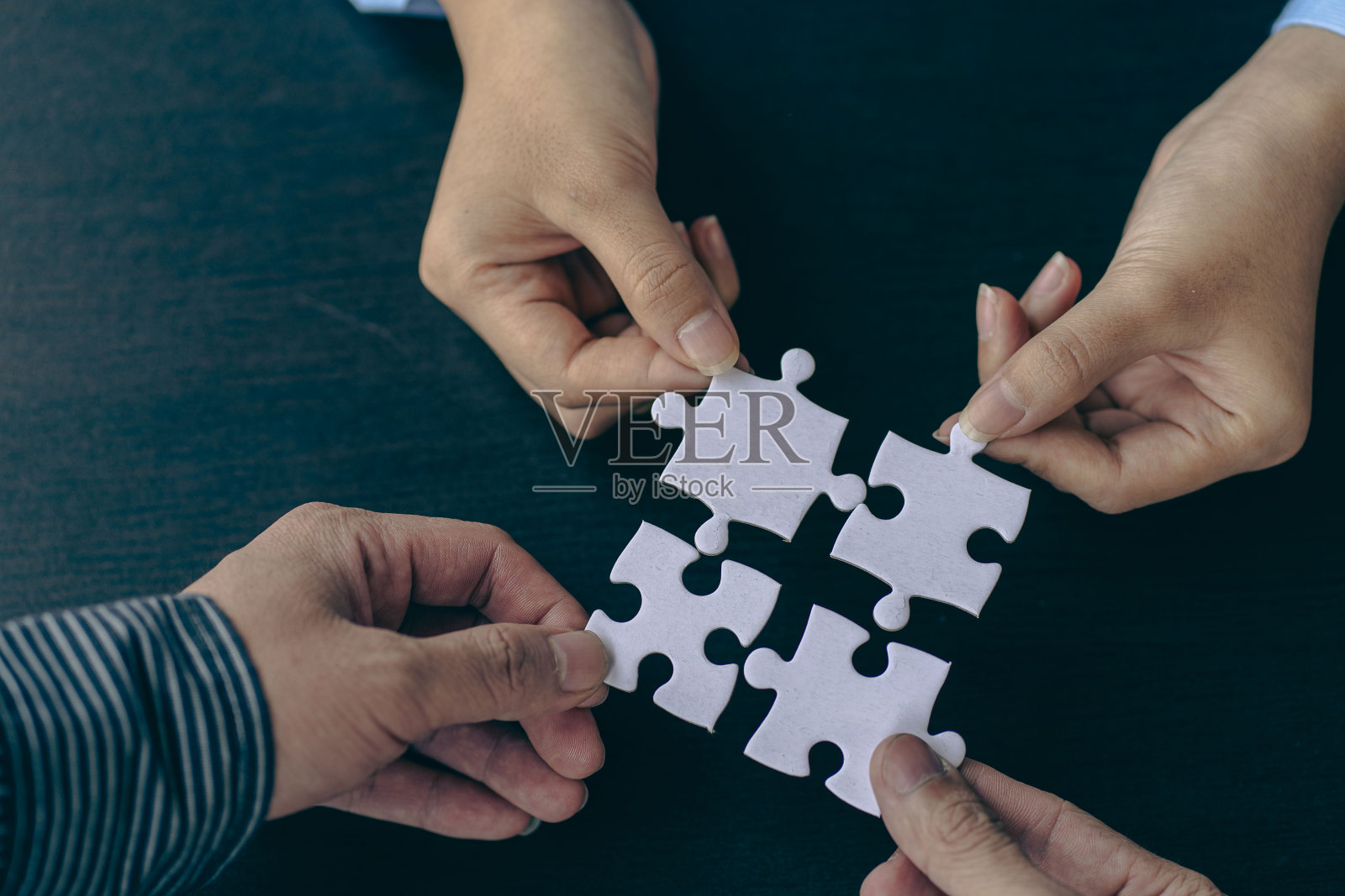 人们手里拿着一个拼图。商业解决方案，成功和战略。一群商人在组装拼图照片摄影图片