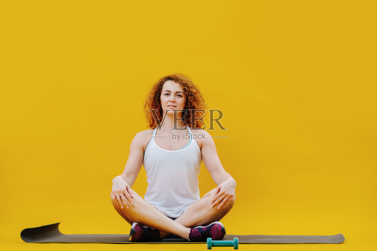 看着镜头，年轻女子盘腿坐在瑜伽冥想姿势照片摄影图片