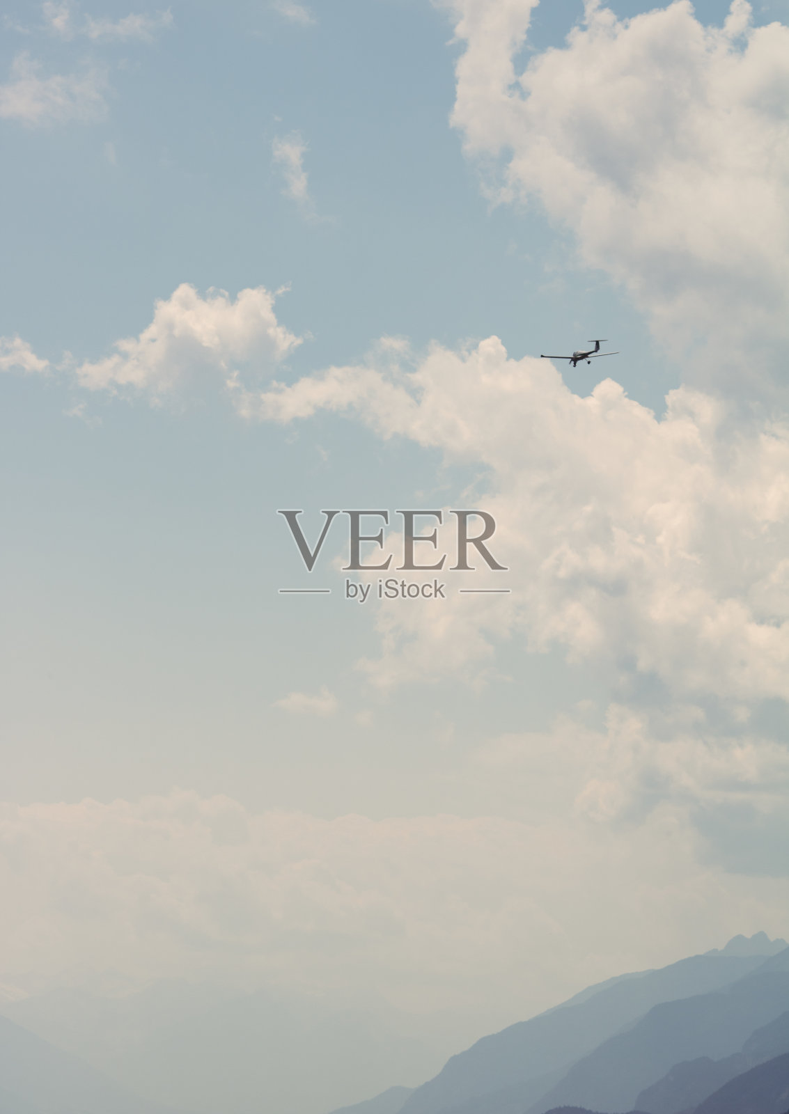 一架轻型飞机在山的轮廓上飞向天空的垂直镜头照片摄影图片