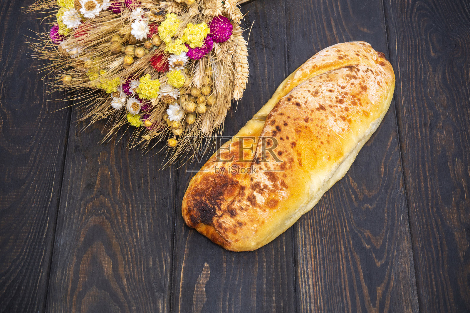 一条乌克兰民族面包和一束干花放在黑色古董桌上照片摄影图片