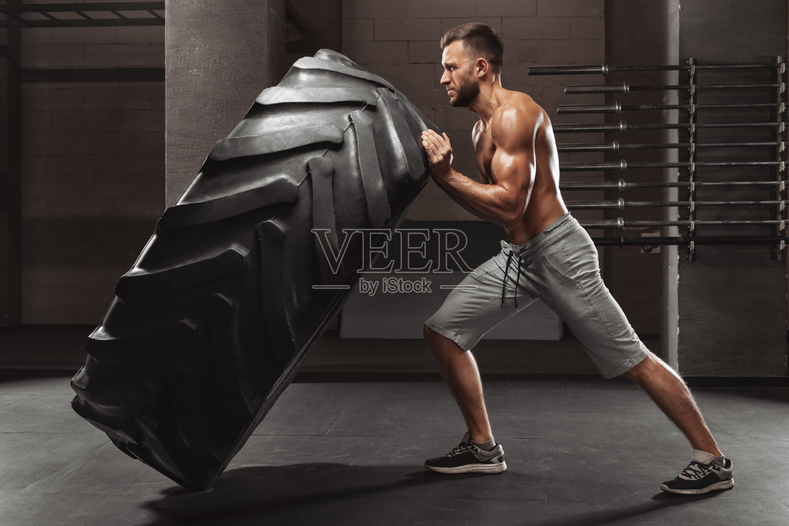 肌肉发达的男人在健身房锻炼，翻转轮胎，强壮的男性裸露的躯干照片摄影图片