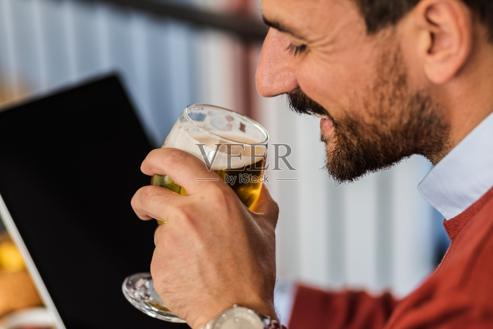 一个商人在餐馆边喝啤酒边用iPad的特写照片摄影图片