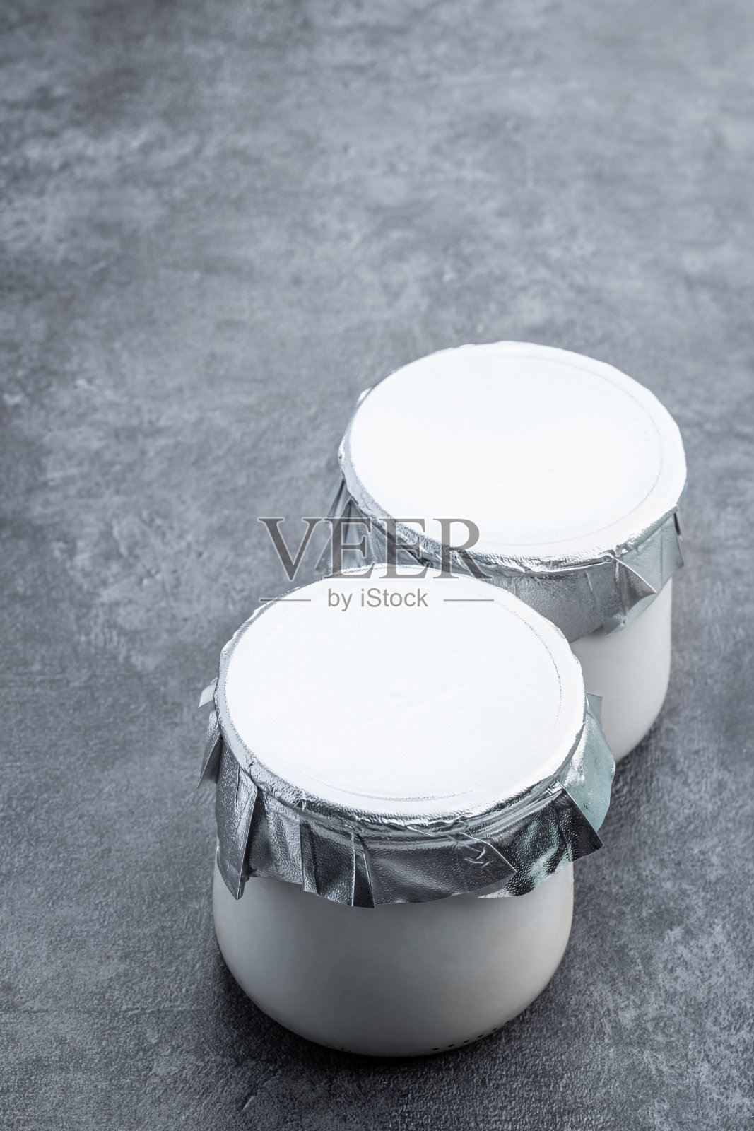 新鲜天然的自制有机酸奶在灰色背景的玻璃罐中照片摄影图片